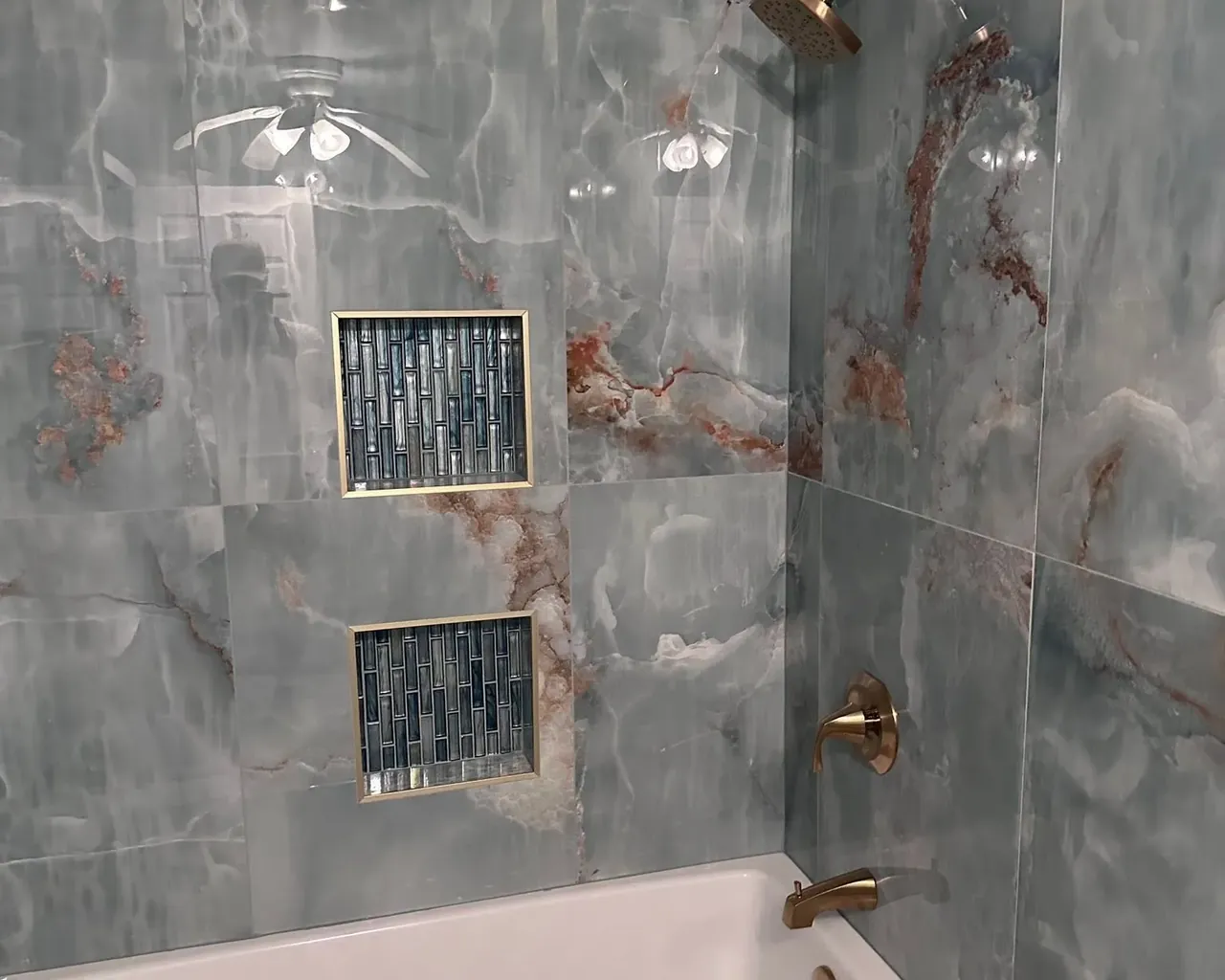 Blue onyx tile tub-shower with niches and brass fixtures, C&A Roofing & Construction