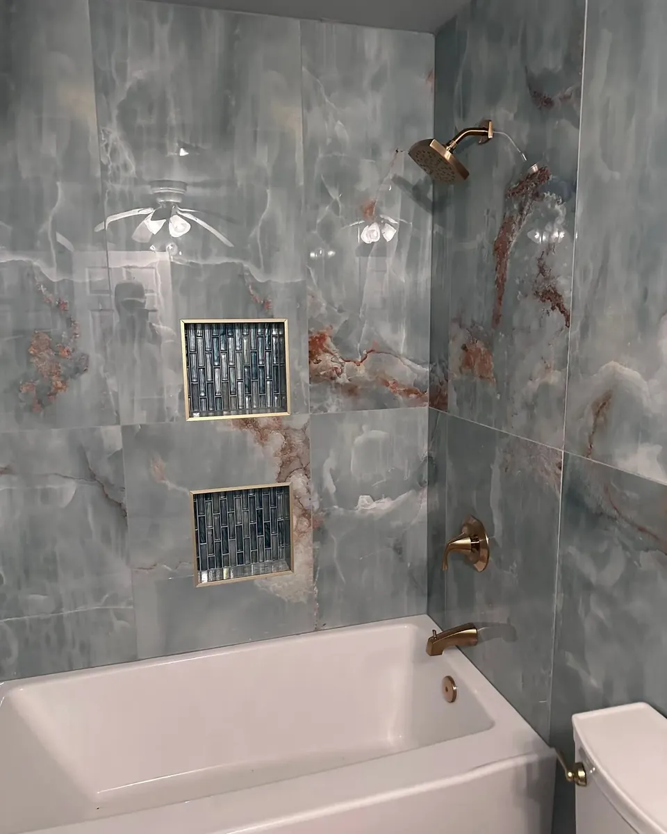 Blue onyx tile tub-shower with niches and brass fixtures, C&A Roofing & Construction