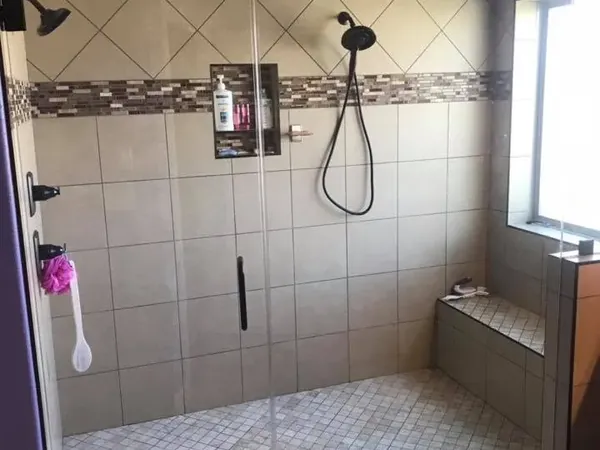 Tiled walk-in shower with frameless glass door and bench, C&A Roofing & Construction